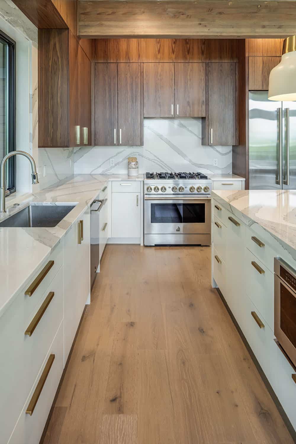 Galley-style kitchen with white cabinetry, stainless gas range, and wood-look flooring