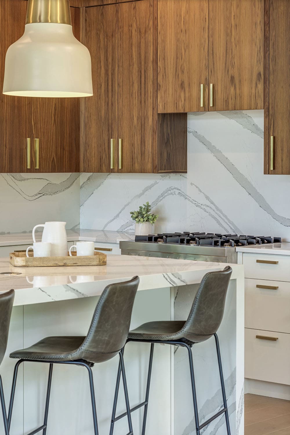 Close-up of kitchen island with leather bar stools and marble backsplash detail