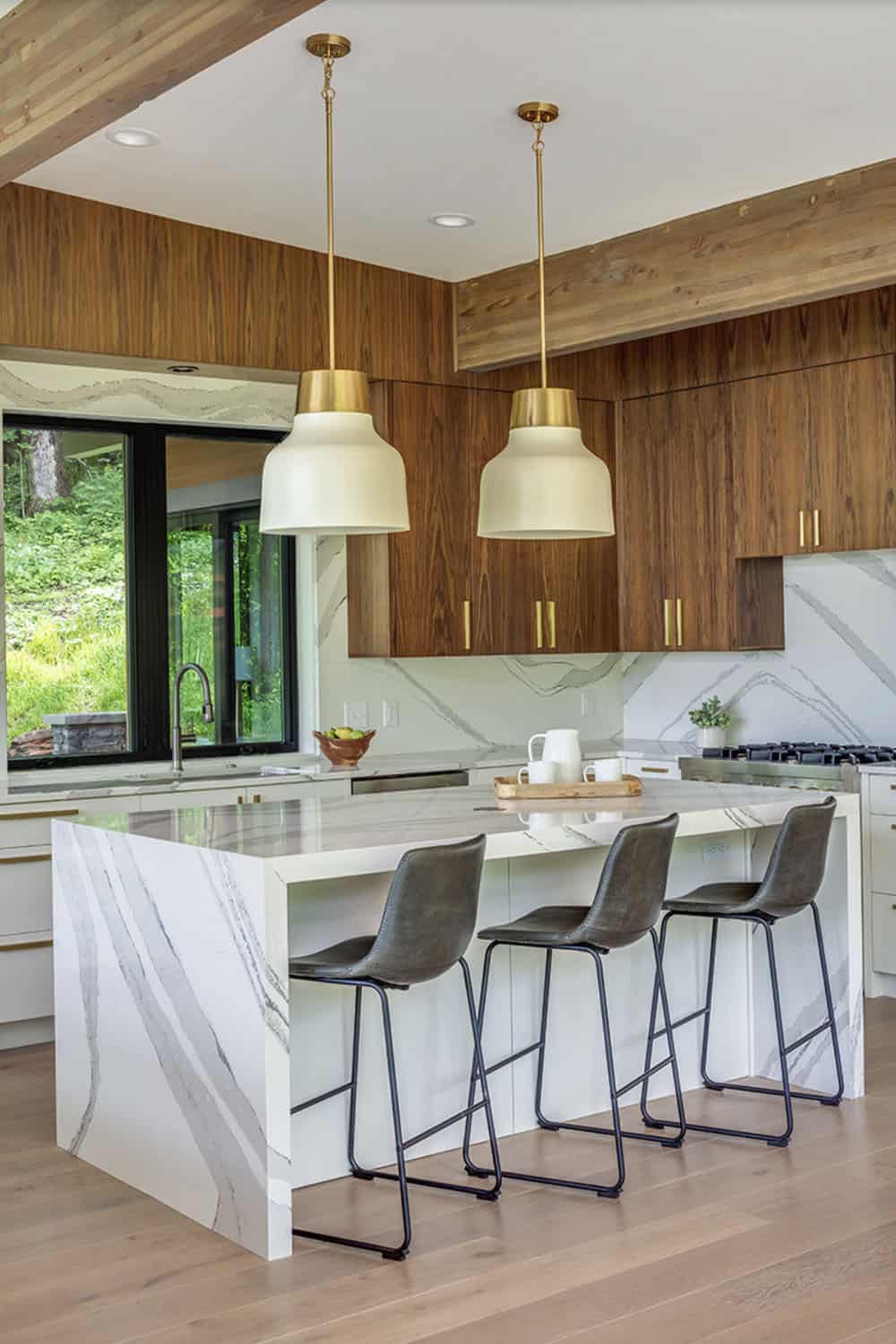 Kitchen island with leather stools, brass pendant lighting, and walnut cabinetry