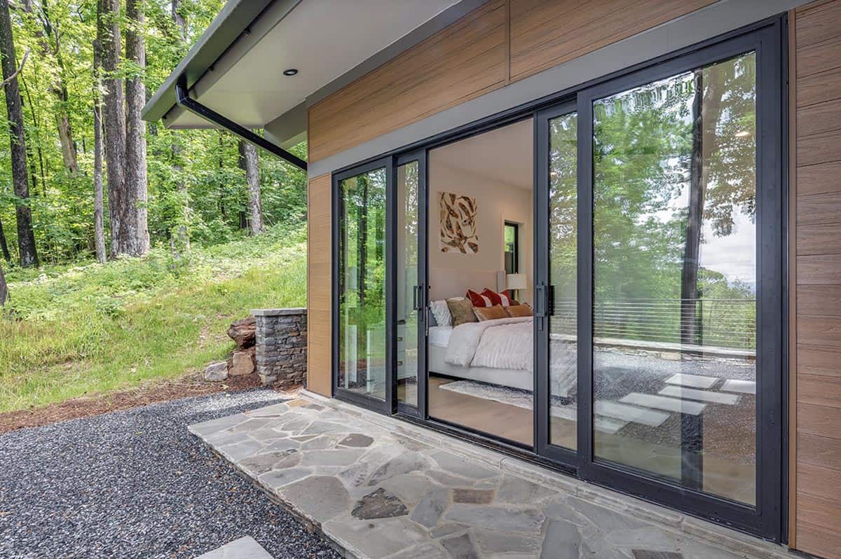 Bedroom seen through open sliding glass doors leading to a stone patio