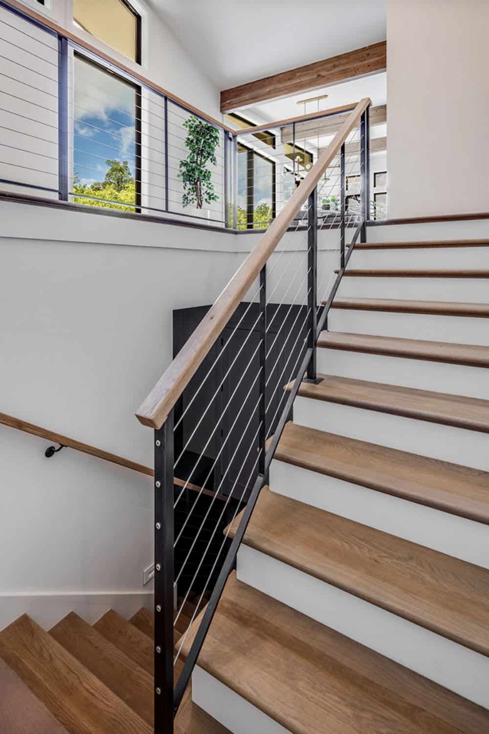 Wooden staircase with cable railing leading to an upper-level loft