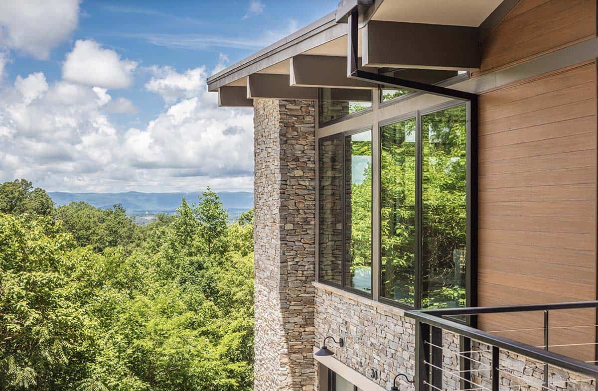 Close-up exterior view of stone column and wood siding with sweeping mountain and treetop views
