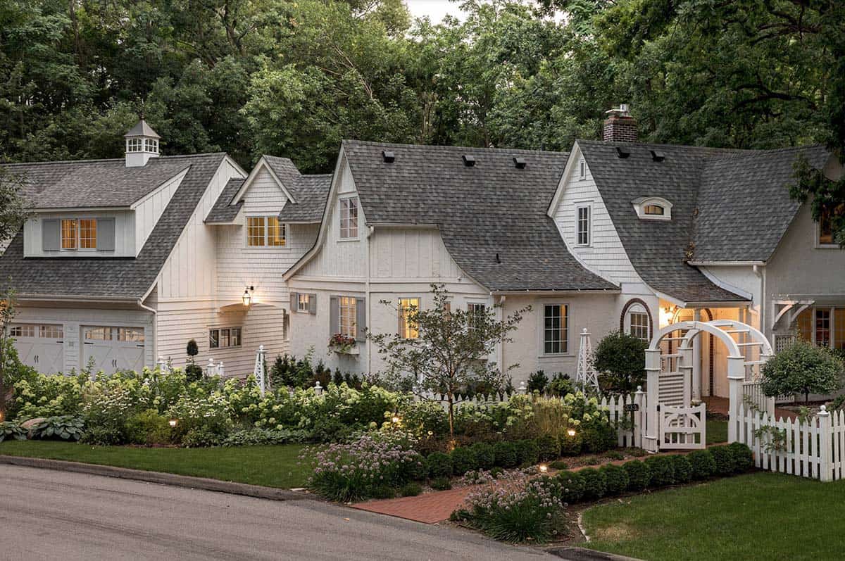 White cottage-style home exterior at dusk with lush front garden and white picket fence, Minnesota