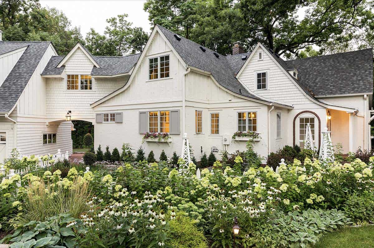 White stucco cottage home surrounded by hydrangeas and coneflowers in a country cottage garden, Minnesota