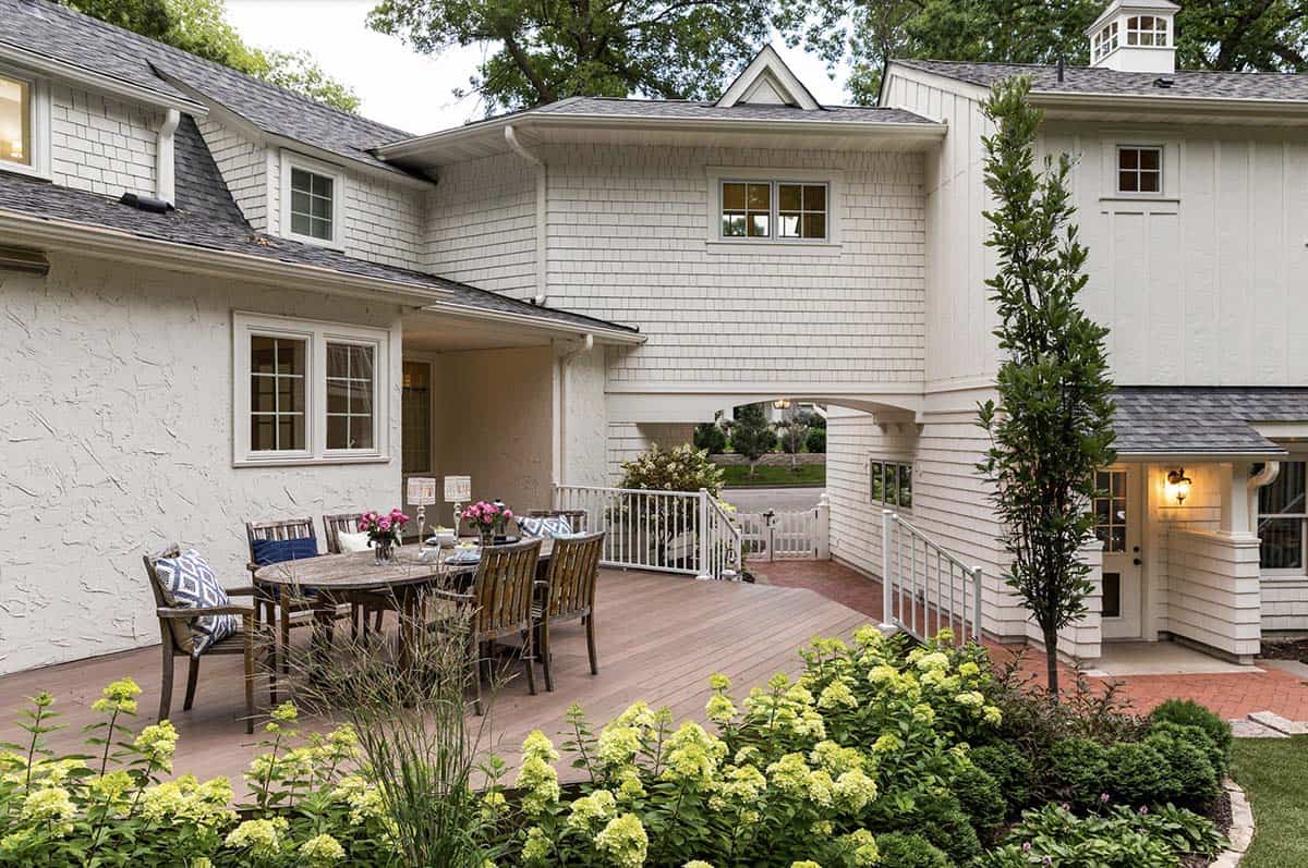 Outdoor dining deck with round table and chairs overlooking hydrangea garden beds