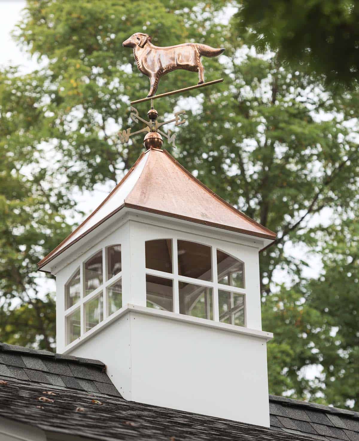 Close-up of white cupola with copper roof and golden retriever weather vane atop cottage home