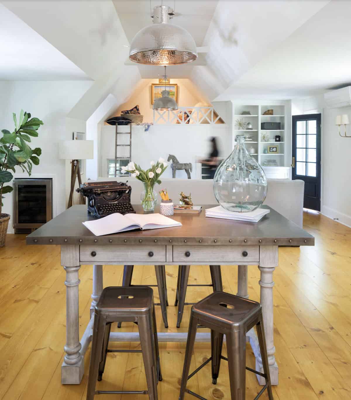Carriage house great room with zinc-top worktable, metal stools, loft ladder, and wide plank floors