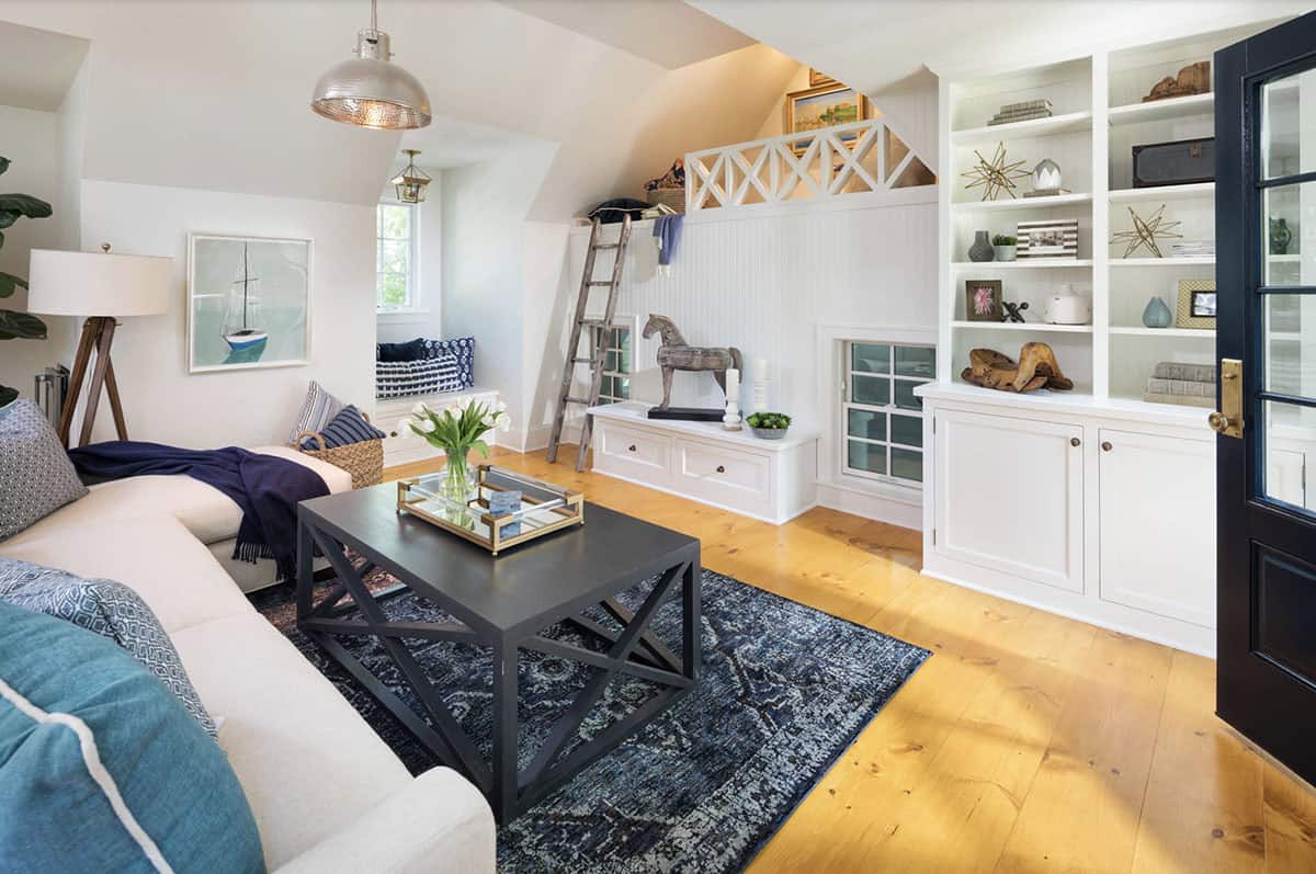 Carriage house living room with navy rug, built-in shelves, loft with ladder, and hammered dome pendant
