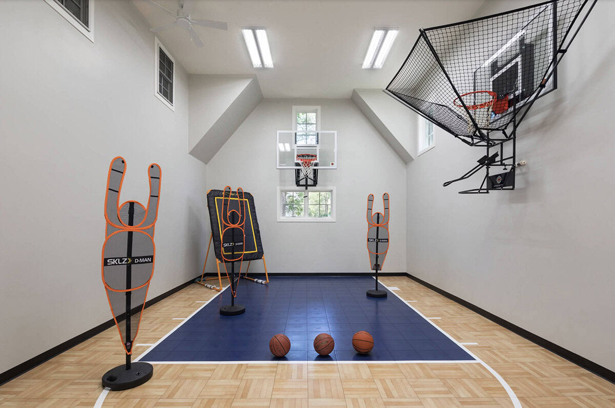 Indoor basketball court with hardwood floor, blue key, wall-mounted hoops, and SKLZ training equipment
