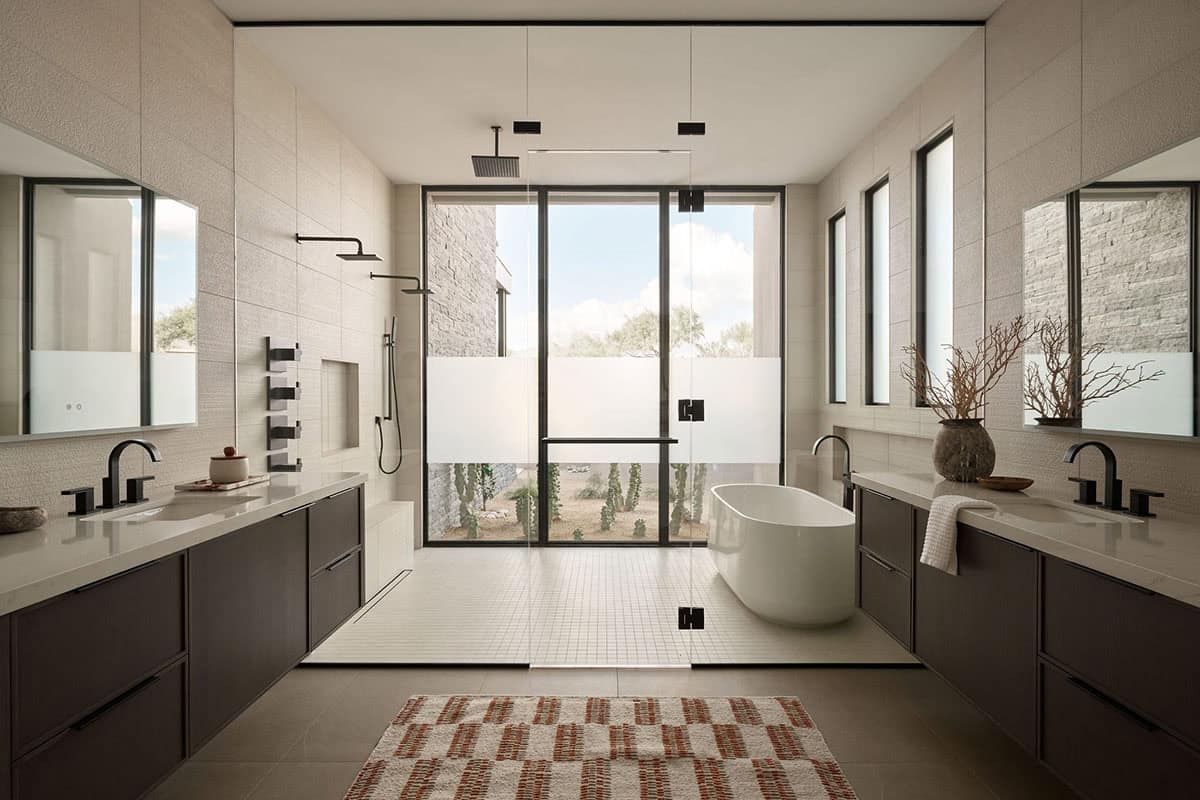 Primary bathroom with dual floating vanities, freestanding soaking tub, glass-enclosed wet room, matte black fixtures, and private cactus garden view