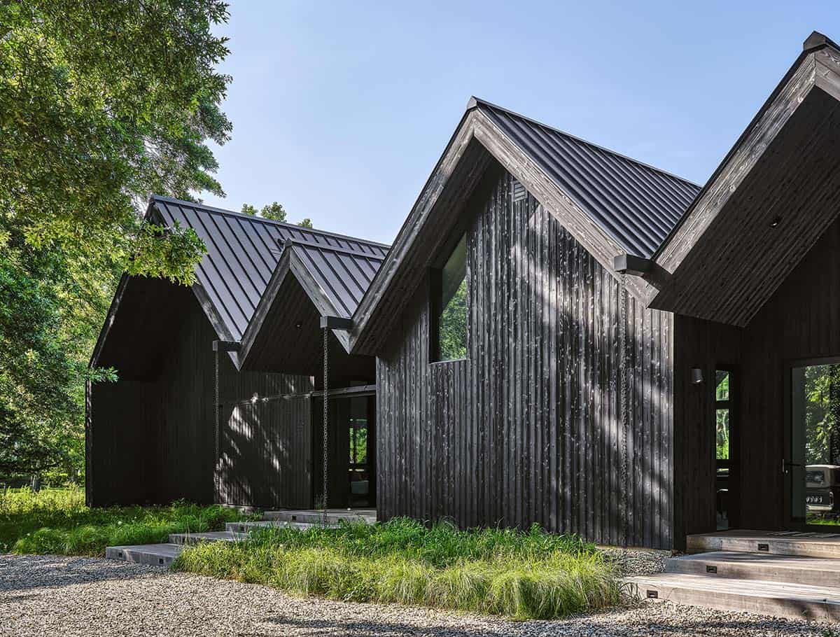 Side view of the charred timber facade showing staggered gable roofs and standing-seam metal roofing