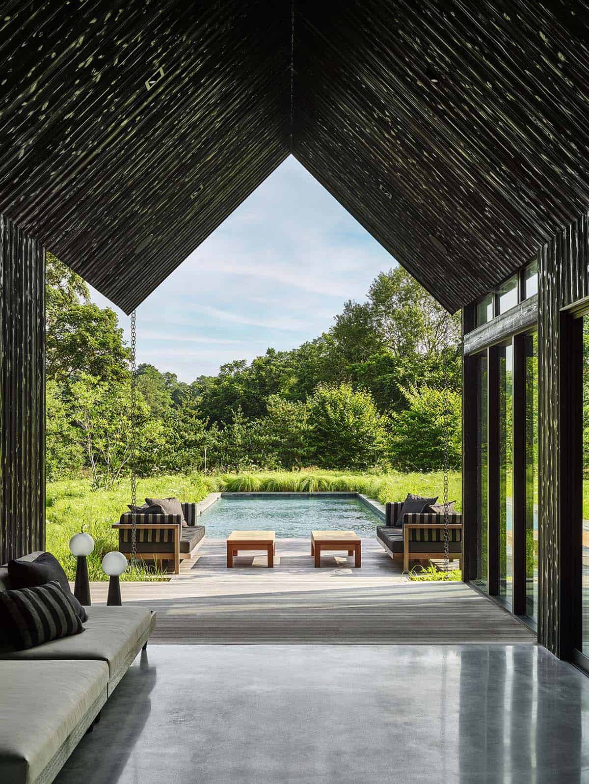 Interior view from a covered breezeway looking out toward the pool, deck, and meadow