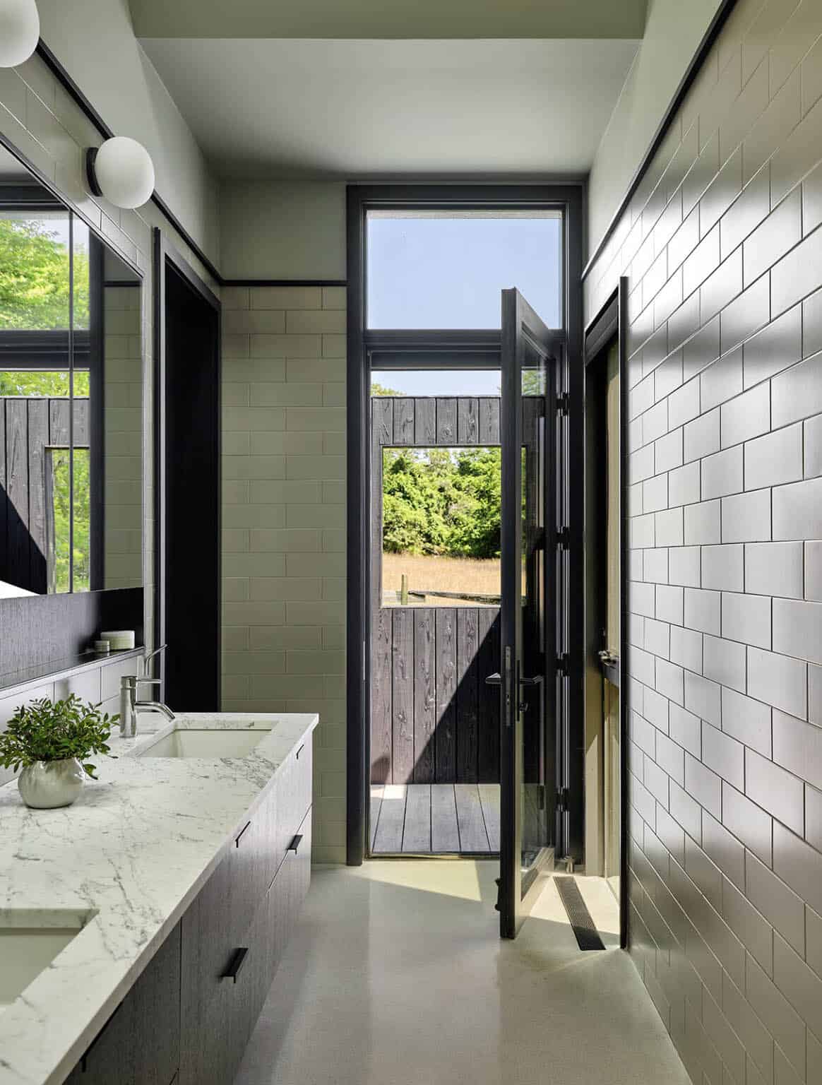 Bathroom with marble vanity, subway tile walls, and a glass door opening to a wood deck