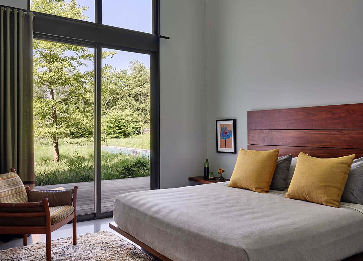 Bedroom with wood headboard, mustard pillows, and a glass door opening to the pool deck
