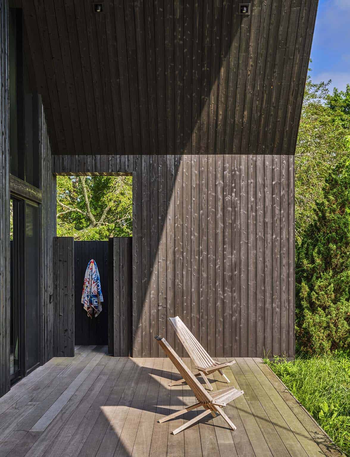 Covered deck nook with two folding wood chairs and a towel hanging in an outdoor shower stall