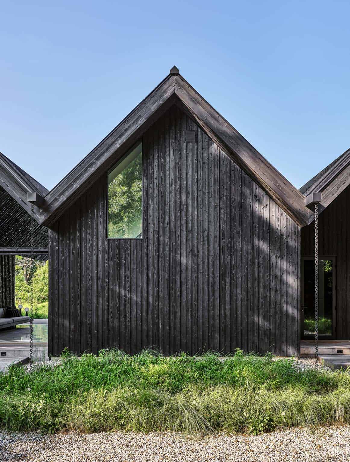 Close-up of a charred wood gable end with a single angled window between two connected structures