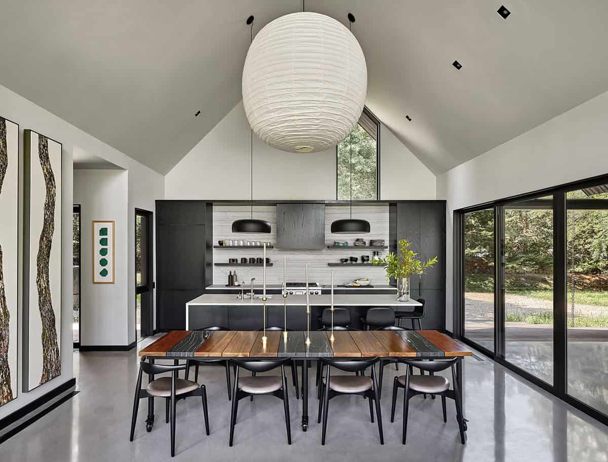 Open kitchen and dining area with vaulted ceiling, large paper lantern, and dark cabinetry