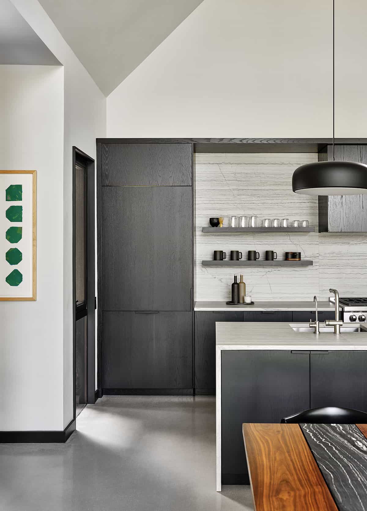 Kitchen island and dark wood cabinetry with marble backsplash, open shelving, and pendant light