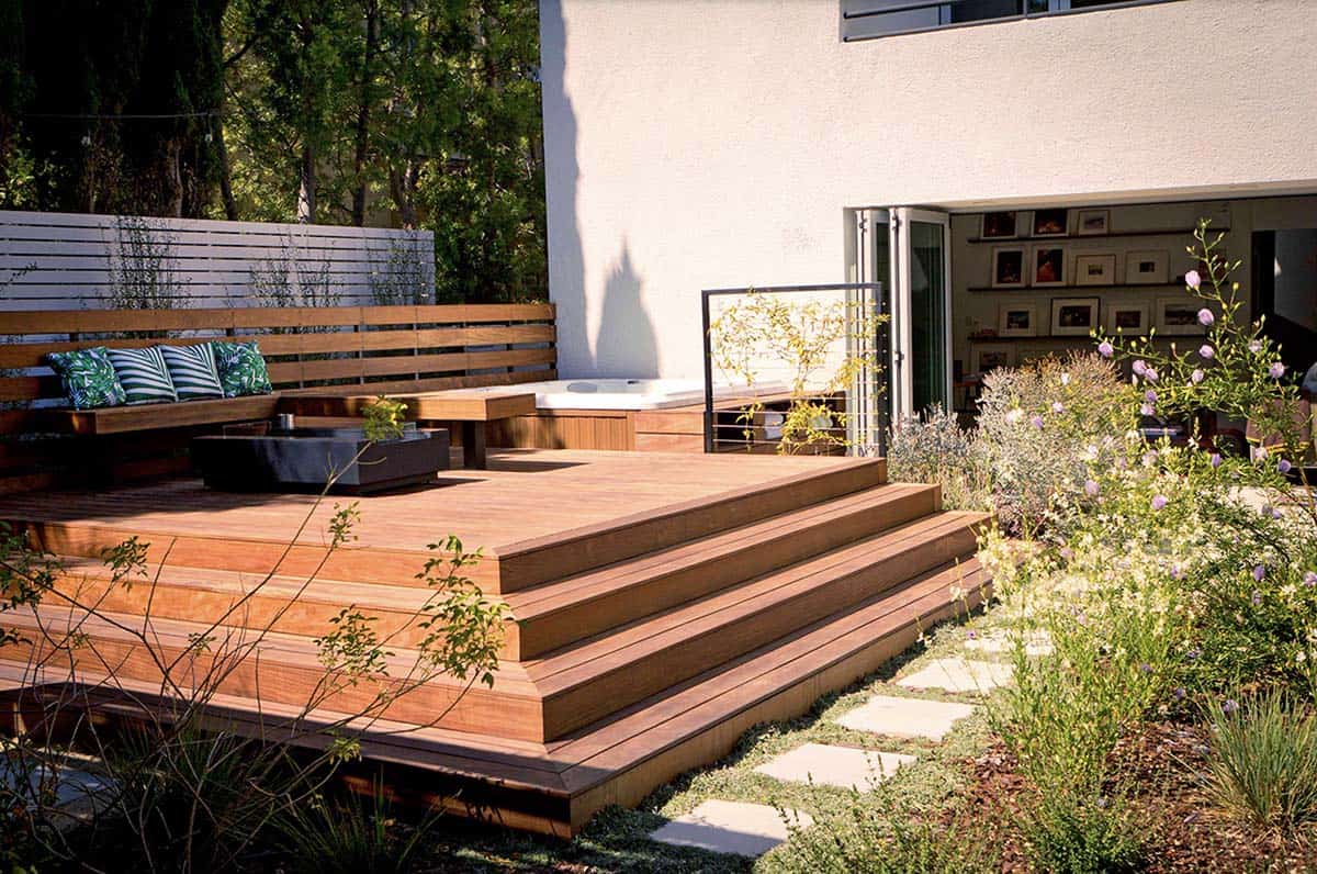 A built-in hot tub deck with cable railing, climbing jasmine, and an English garden-inspired lounge area surrounded by drought-tolerant plantings in Santa Monica, California