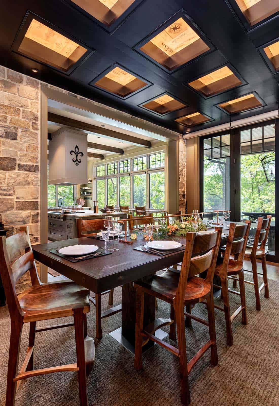 Dining area with dark coffered ceiling, tall bar-height table, wood chairs, and open kitchen view