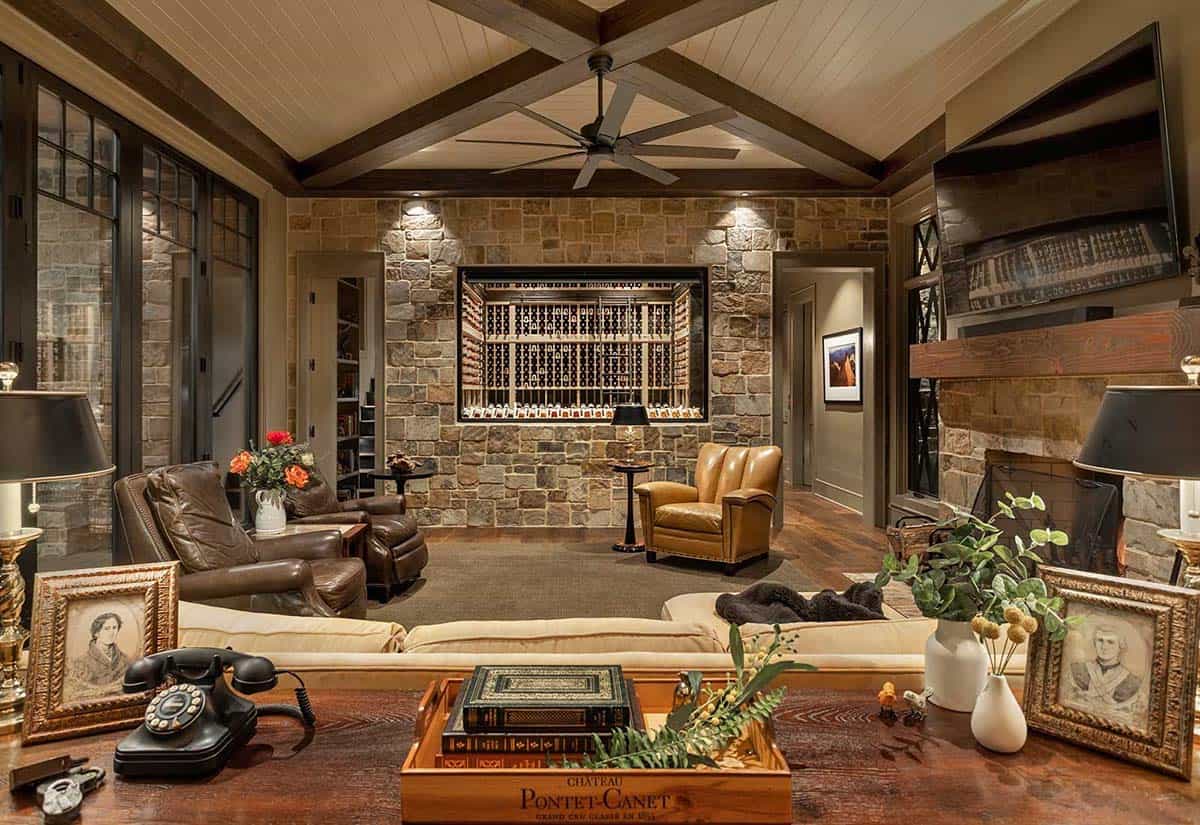 Rustic living room with vaulted ceiling, stone walls, built-in wine display, and leather seating