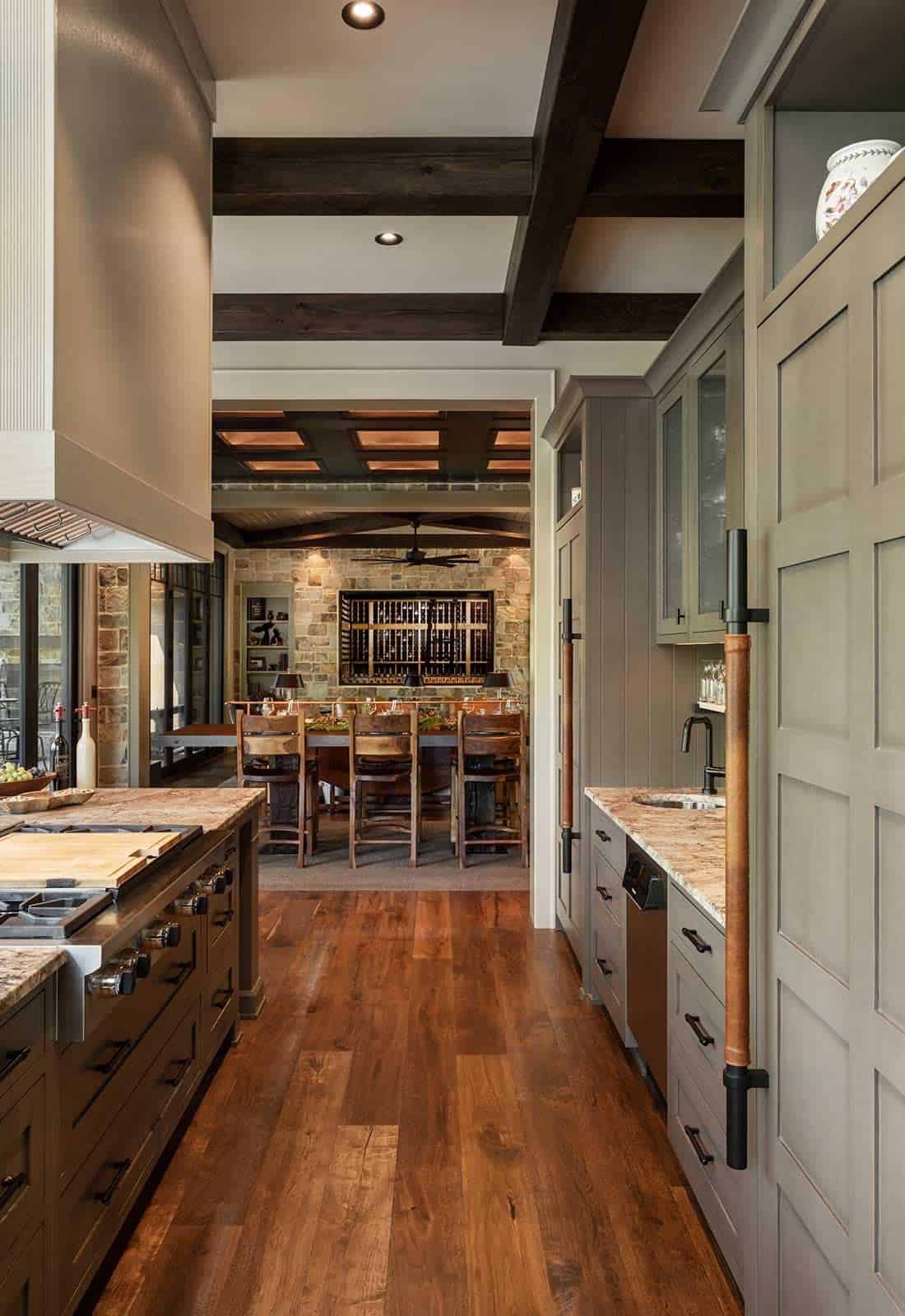 Kitchen hallway with sage green cabinetry, dark exposed beams, and view through to dining and wine room