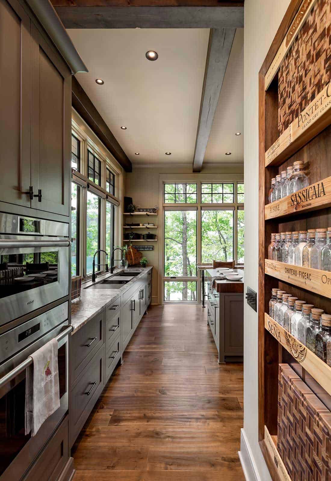 Galley kitchen with gray-green cabinets, Wolf appliances, and wine crate shelving displaying glass jars
