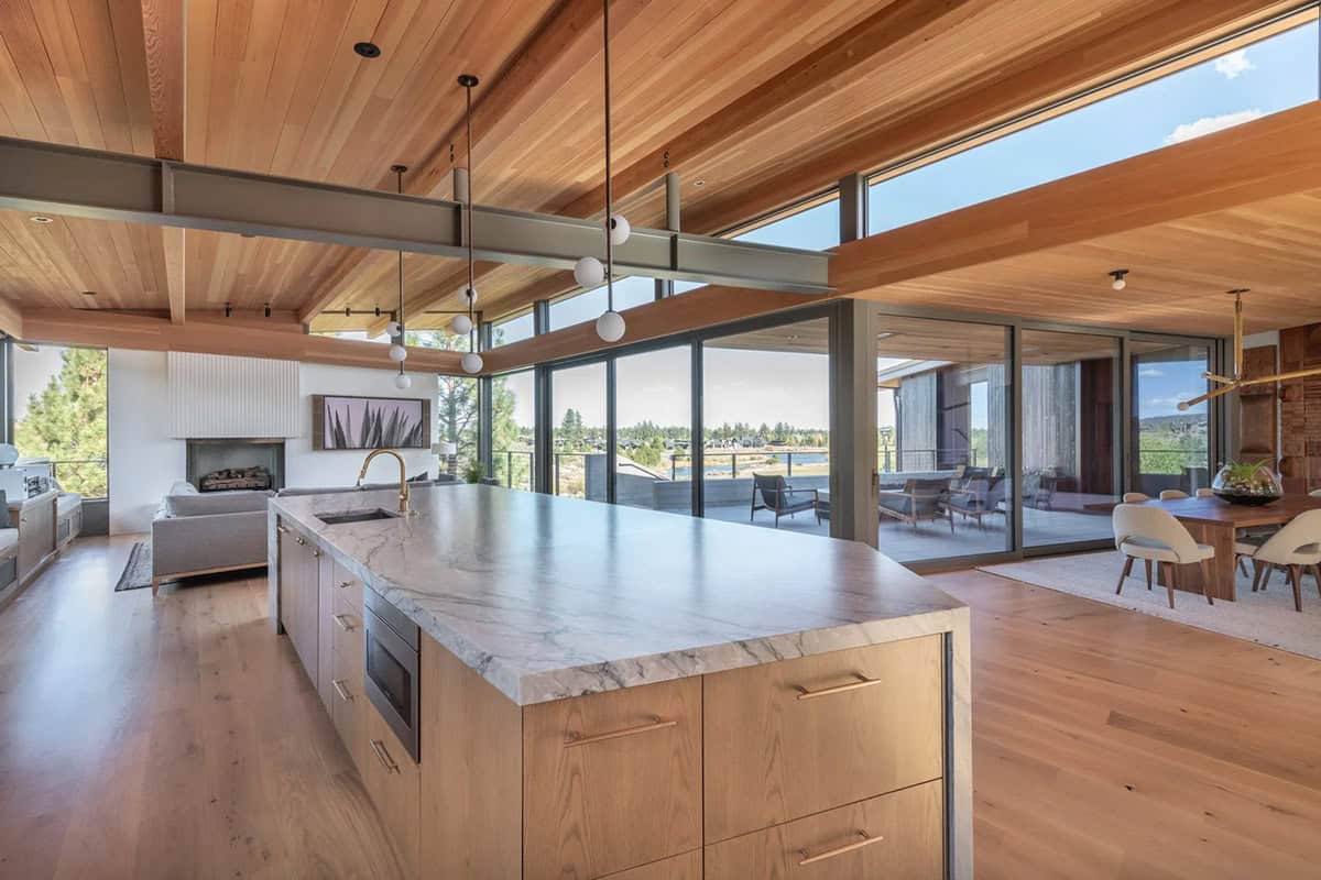 Kitchen island overlooking open-plan living and dining with floor-to-ceiling windows
