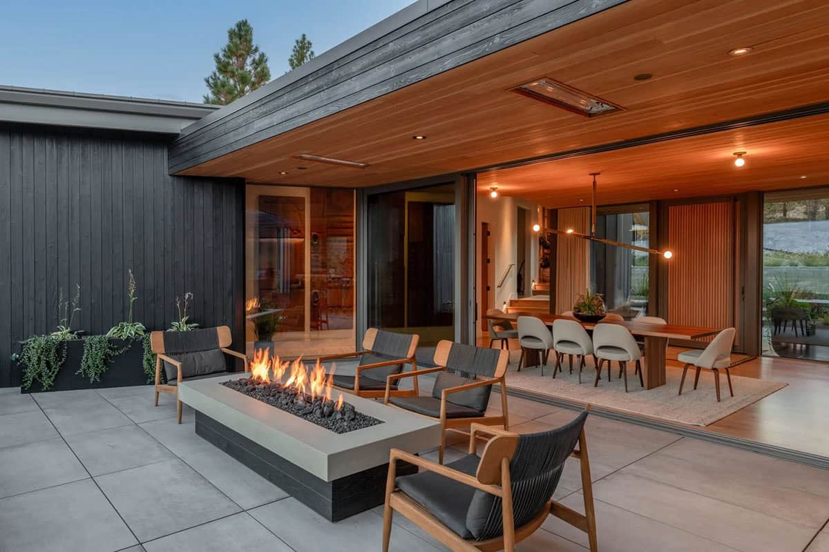 Covered patio with concrete fire table at dusk, open to indoor dining room