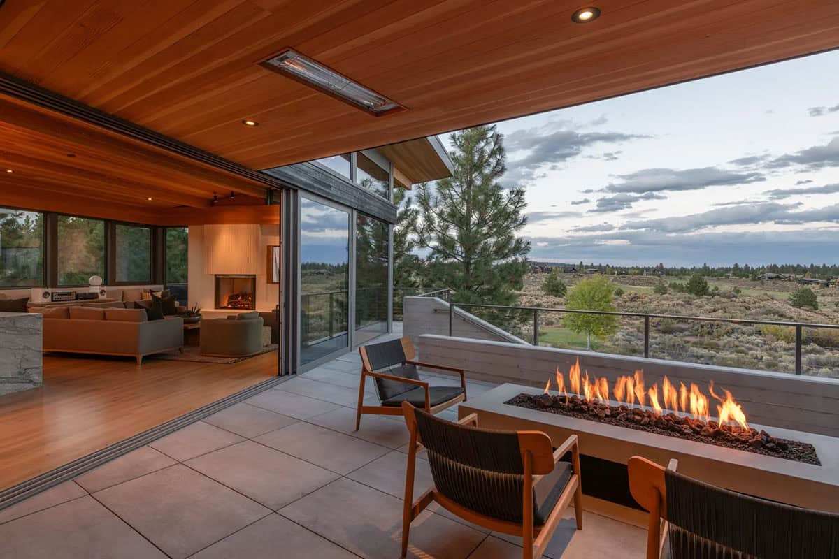 Outdoor terrace with linear gas fire pit overlooking high desert scrubland at dusk