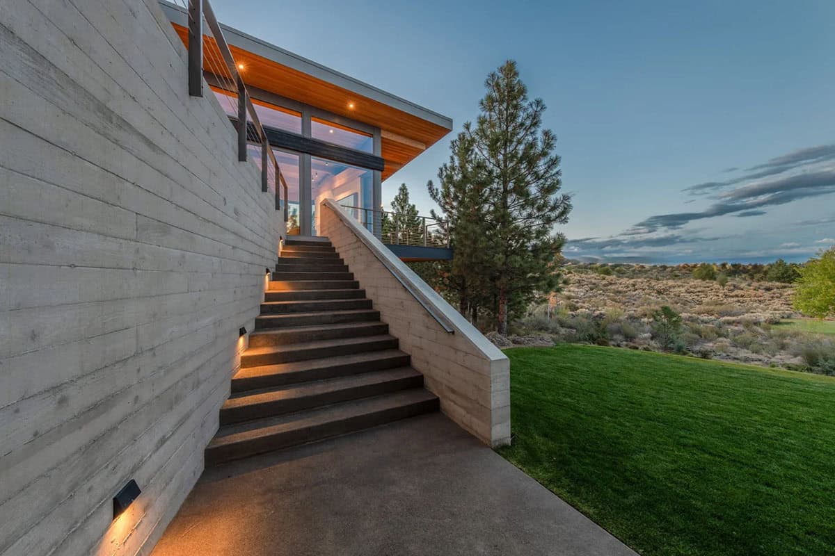 Concrete staircase leading to covered terrace overlooking high desert scrubland at dusk