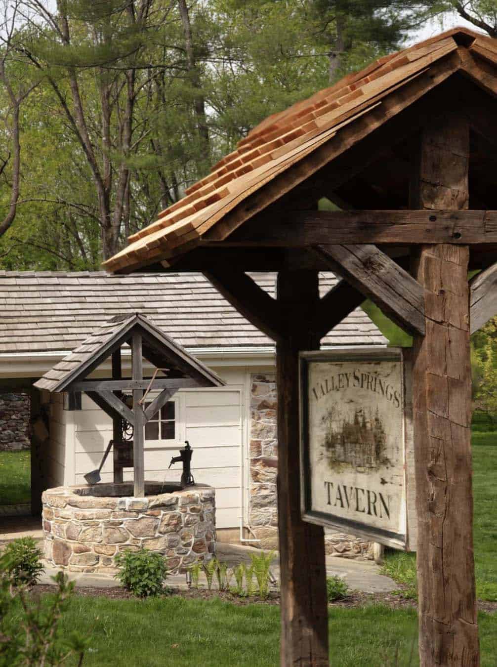Stone wishing well with wood-shingled roof beside the Valley Springs Tavern sign