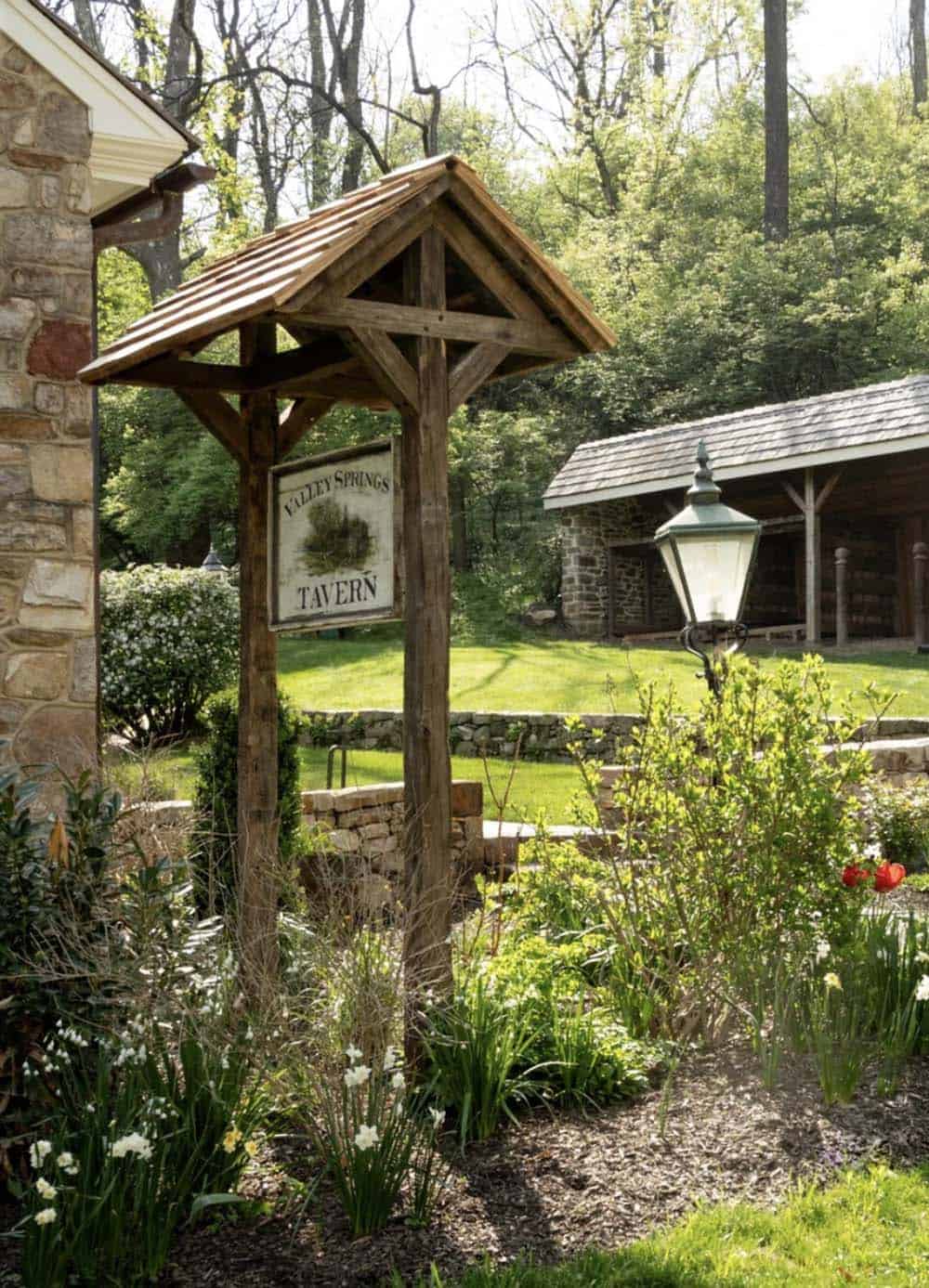 Wooden sign post with shake roof in front of stone pavilion and garden lantern