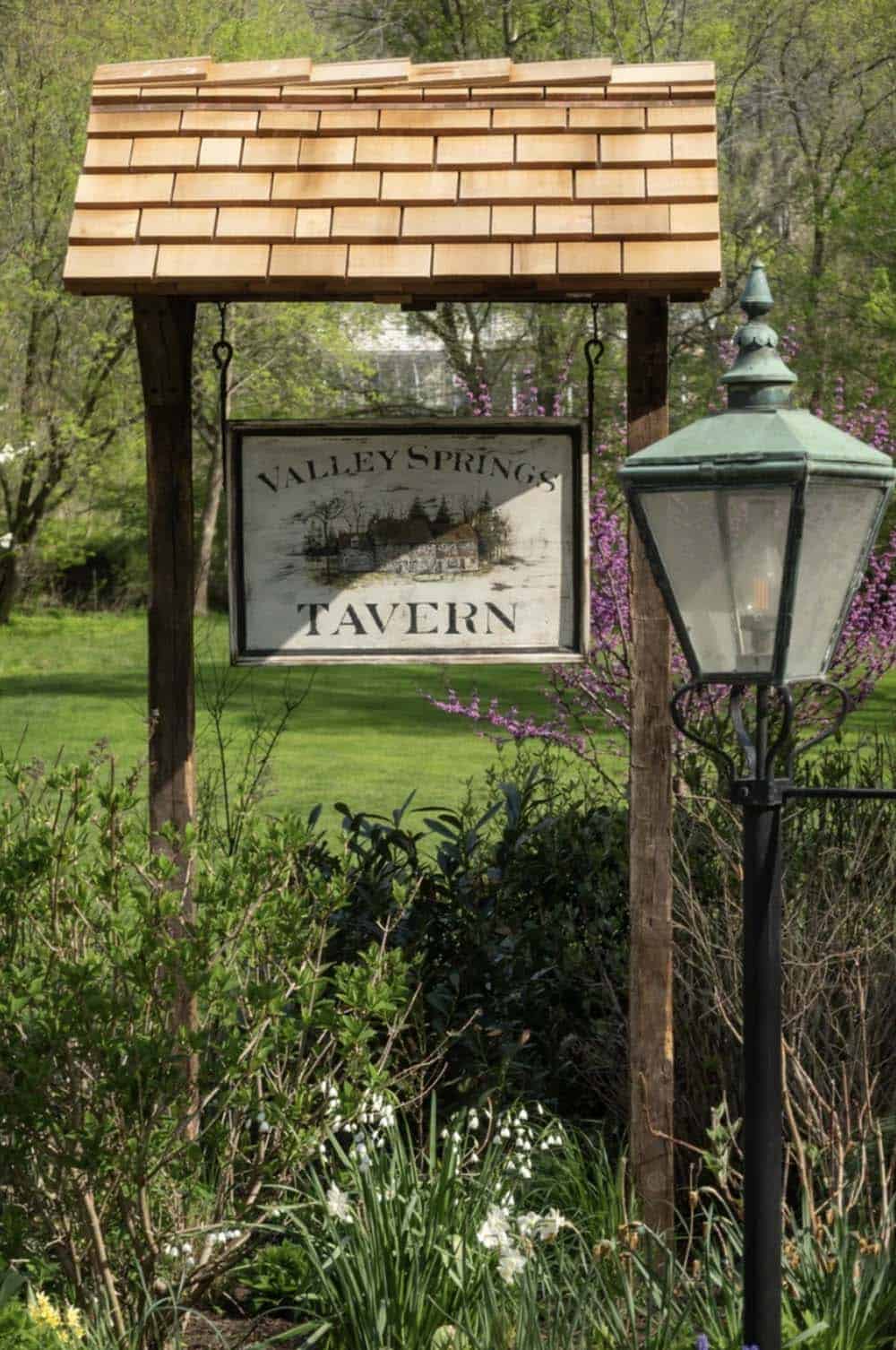 Close-up of wood-shingled sign post holding the "Valley Springs Tavern" sign at dusk