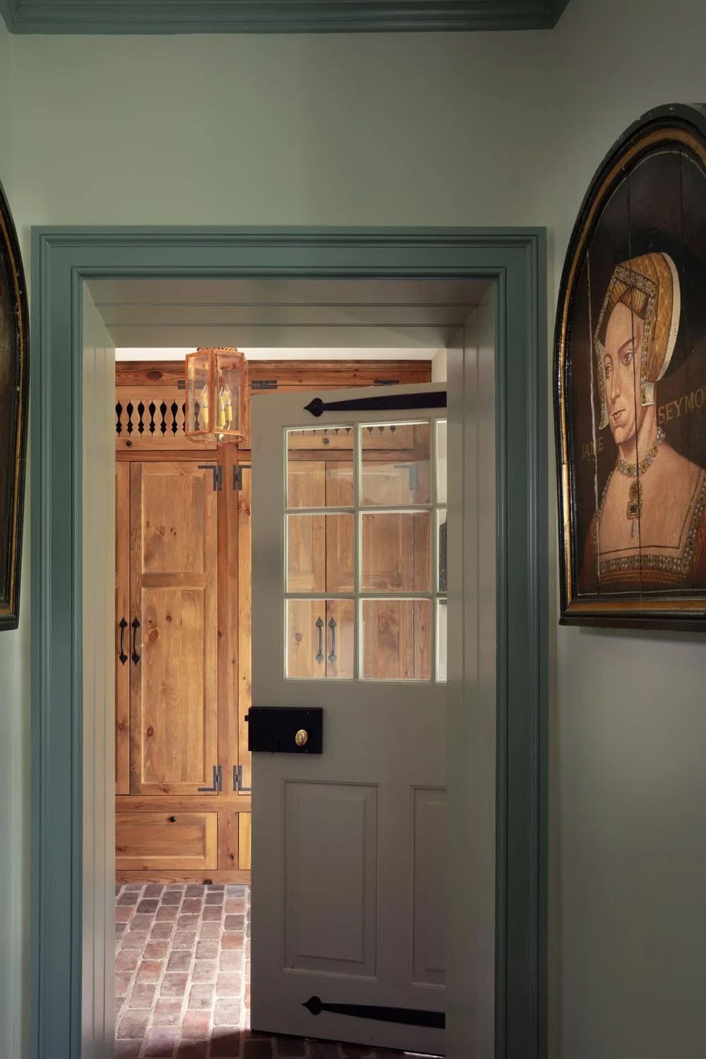 View through open door into rustic pine-paneled mudroom with brick floor