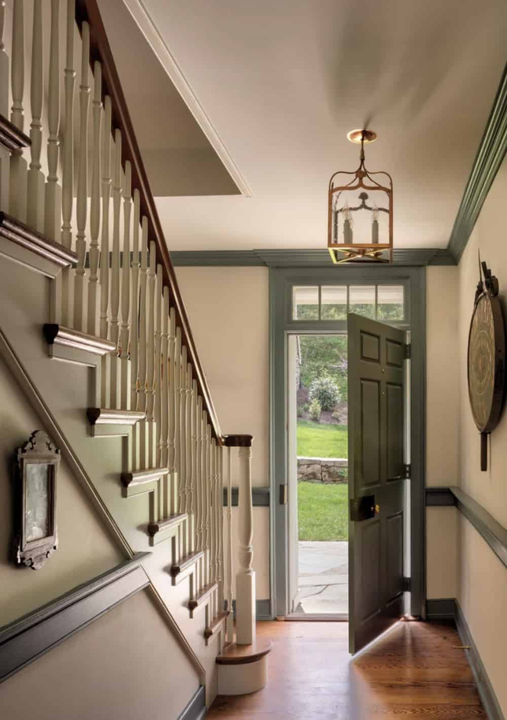 Staircase and front entry hall with open door framing a view of the lawn