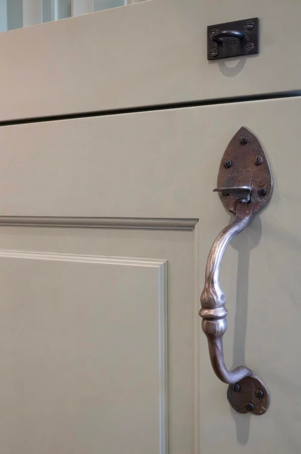 Detail of wrought-iron drop handle on a painted cabinet door