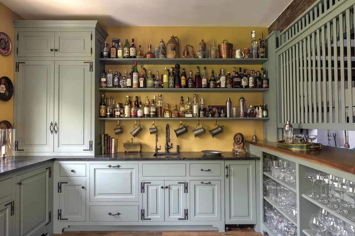 Home bar cabinetry with open shelving holding glassware and bottle collection
