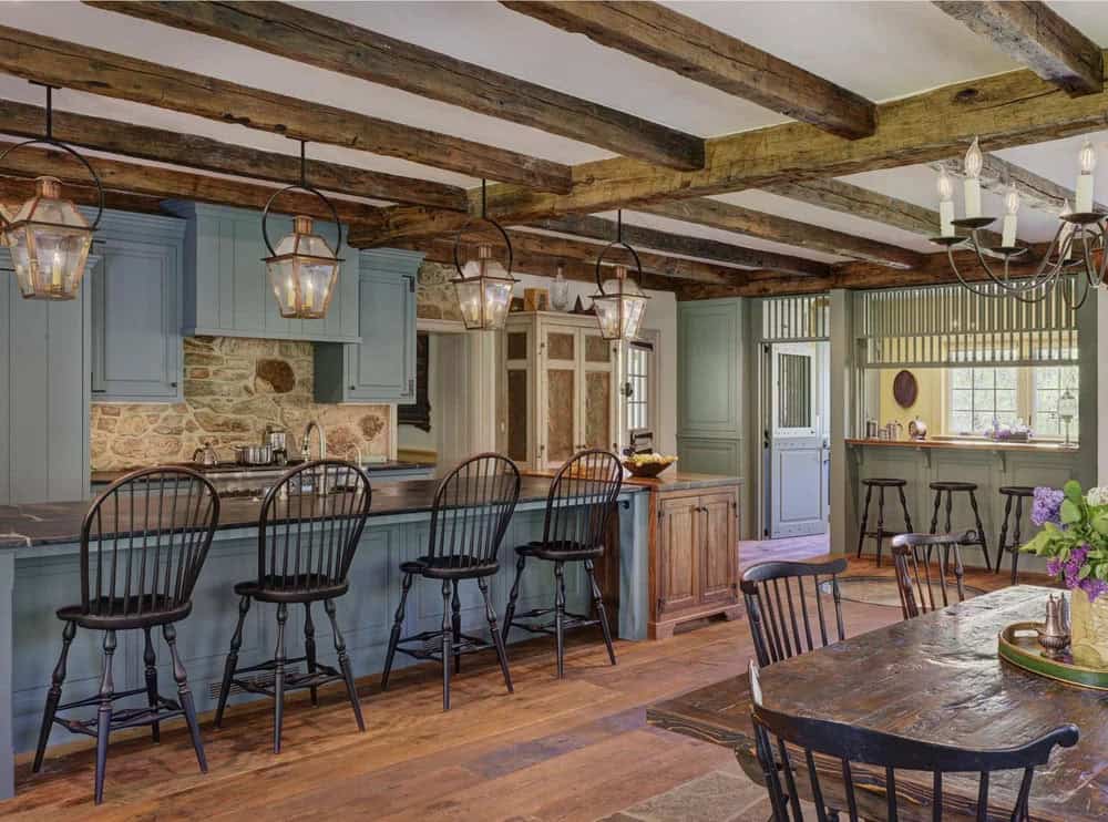 Open kitchen and dining area with exposed beams, copper lanterns, and stone backsplash