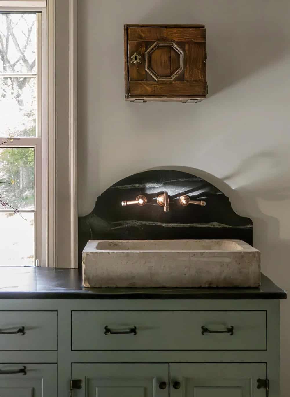 Stone trough sink, soapstone backsplash, and antique wall box