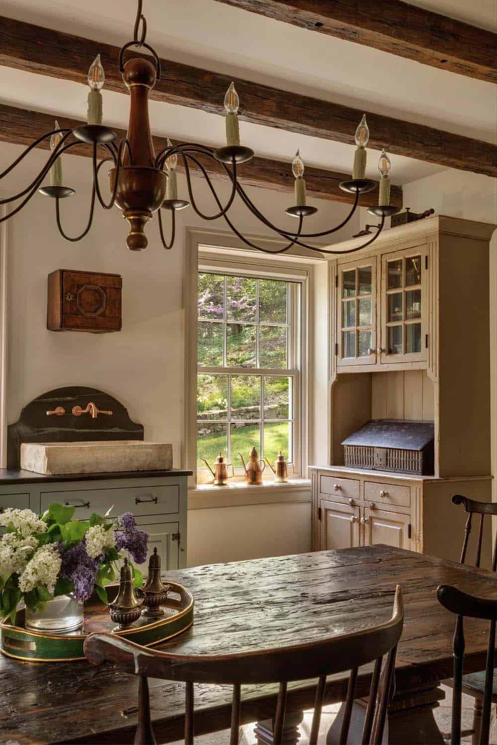 Dining nook with wagon-wheel chandelier, antique hutch, and window seat