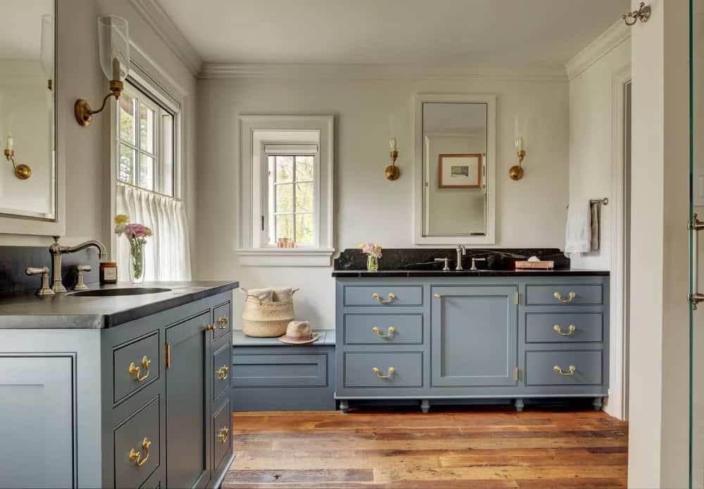 Bathroom with slate-blue vanity cabinets, brass hardware, and dual sinks