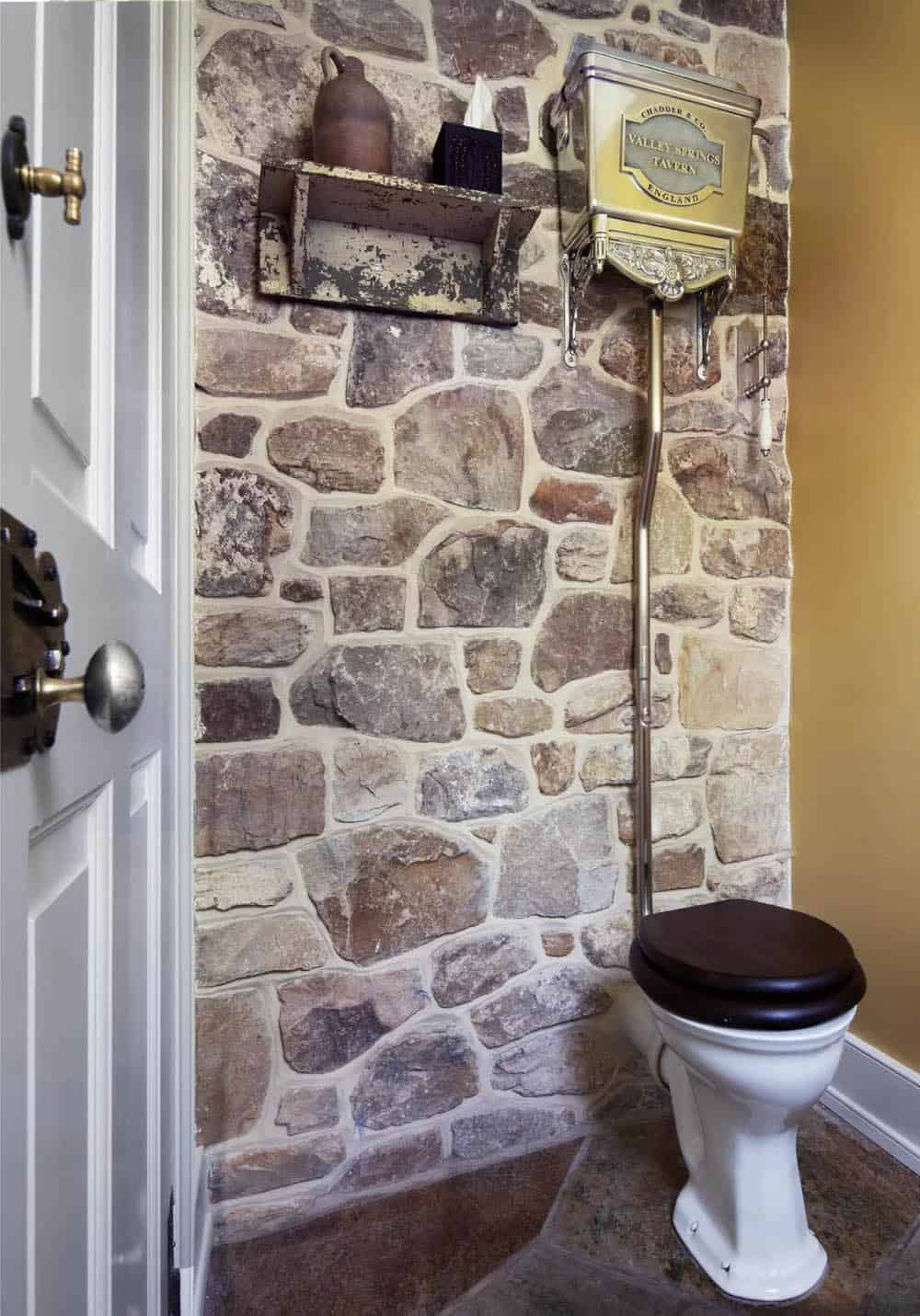 Powder room with stone wall, high-tank pull-chain toilet, and antique shelf Image 20: Mustard-yellow powder room with carved stone sink and Delft-style tile