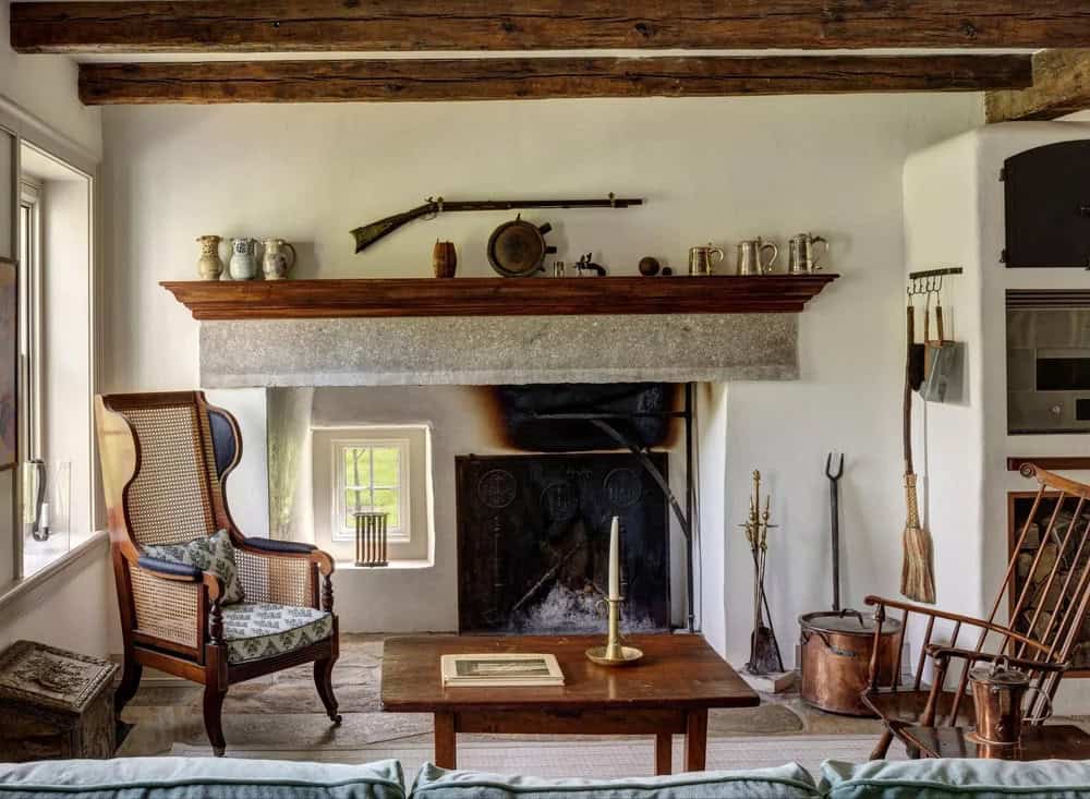 Living room with beehive bake oven fireplace, wood mantel, and antique wing chair