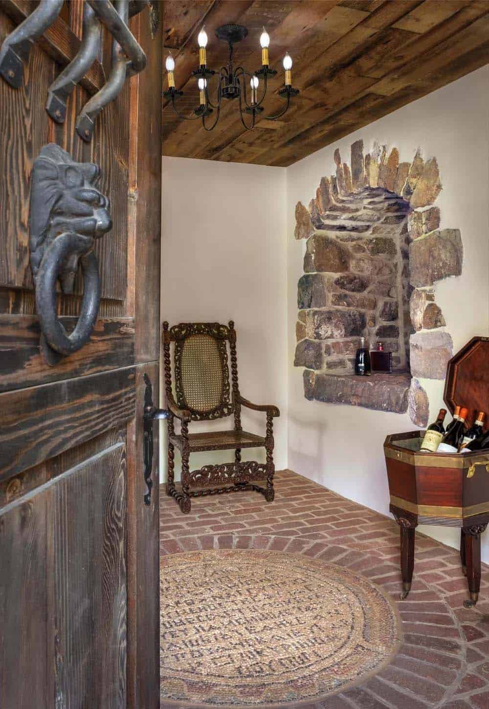 Stone entry nook with wine cooler, carved chair, and arched stone niche under wood ceiling