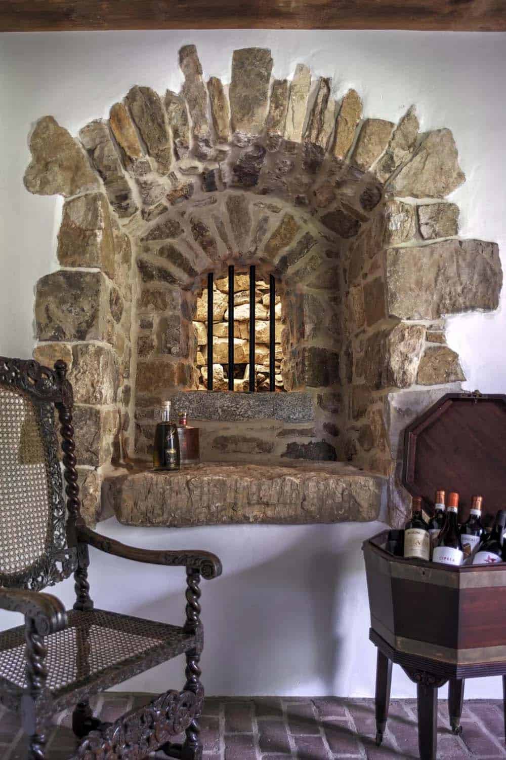 Detail of arched stone wall niche with iron bars and bottles on display