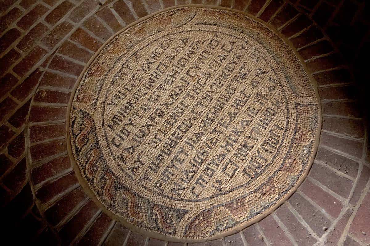 Round decorative mosaic medallion set into a brick floor
