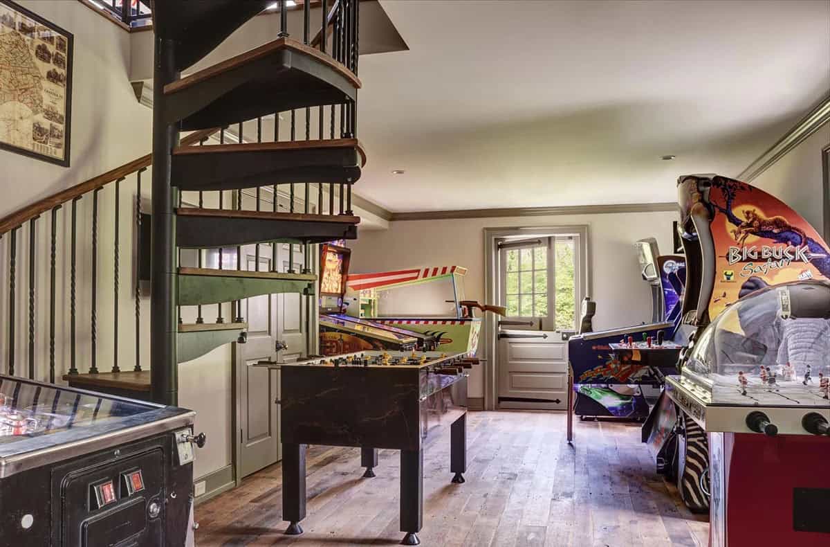 Game room with spiral staircase, foosball table, pinball machine, and arcade cabinets including Big Buck Safari