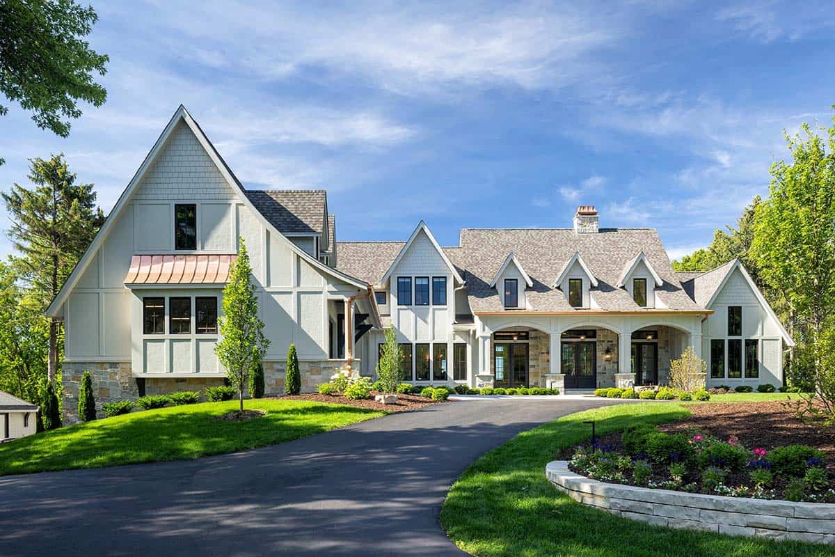 Tudor-style stone and shingle estate exterior with steep gabled roofline and circular driveway