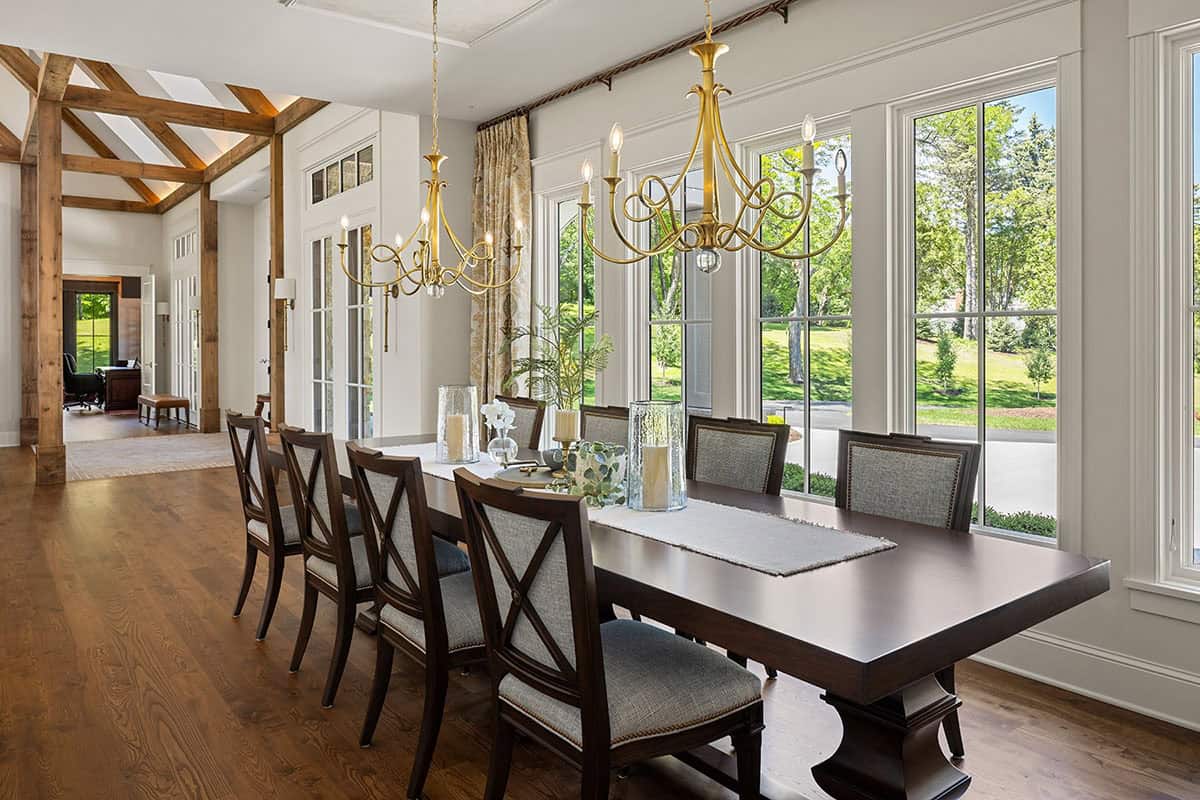 Dining room with brass chandeliers, dark wood table, and wall of windows